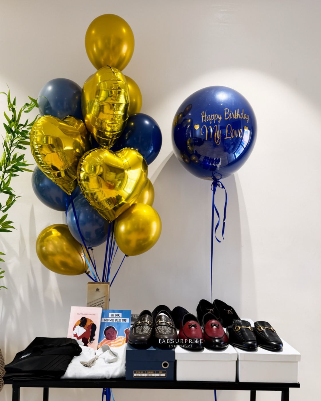 Navy and gold balloon bouquet beside a personalised birthday balloon and boxed gifts