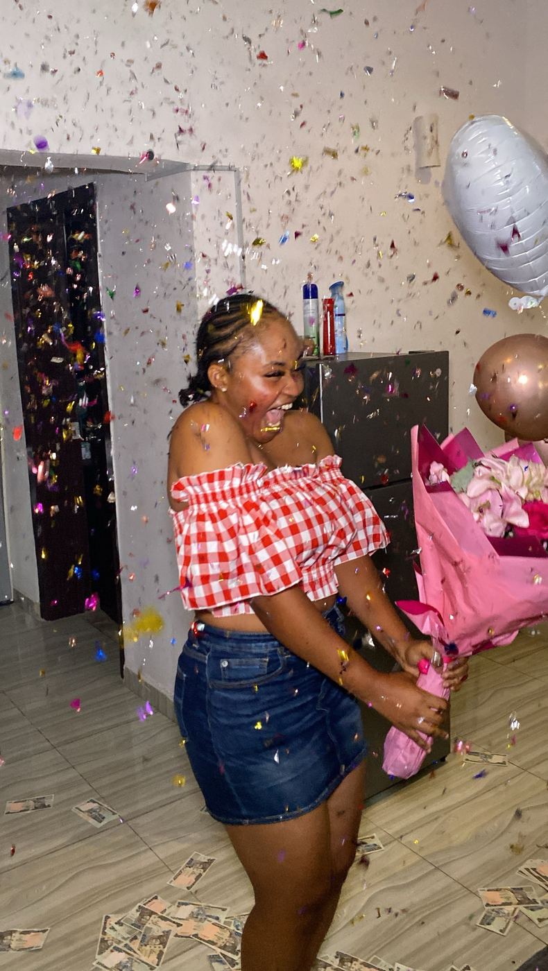 Woman laughing and holding a pink bouquet as confetti falls around her